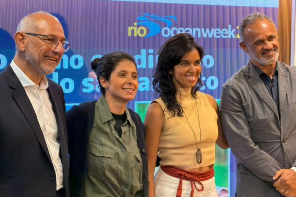 Quatro participantes posam diante do painel da Rio Ocean Week após debate sobre saneamento básico.